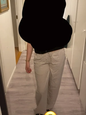 Beiga linnebyxor  - Snygga beiga linnebyxor med avslappnad passform och dragsko i midjan. Byxorna är tillverkade i ett lätt och luftigt linnematerial, perfekta för en chill och stilren look. Elastisk midja för extra komfort.