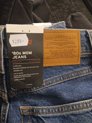 '80s Mom Jeans från Levi's blå - Säljer ett par klassiska '80s Mom Jeans från Levi's i blå denim. Jeansen har hög midja, avslappnad passform över höft och lår samt avsmalnande ben. Snygga kontrastsömmar och ikonisk läderpatch bak. Perfekta för en retroinspirerad look.
