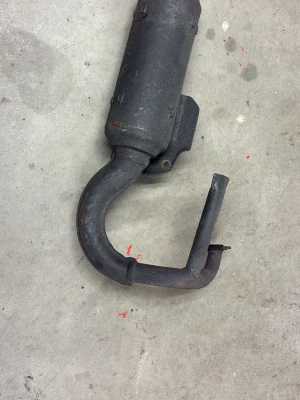 Avgassystem till moped eller scooter - Säljer ett svart avgassystem med böjd form, troligen till moped eller scooter. Tillverkat i metall och har en robust konstruktion med fäste. Perfekt för dig som behöver reservdel till ditt fordon.