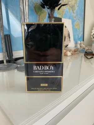 Bad Boy Elixir parfym 50ml - Bad Boy Elixir från Carolina Herrera är en parfym i en elegant svart och guld förpackning. Flaskan rymmer 50 ml och har en lyxig design med tydliga guldkanter och märkets logotyp på toppen. Perfekt för dig som gillar exklusiva dofter.