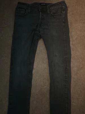 Svarta slim fit jeans Jack & Jones - Snygga svarta slim fit jeans från Jack & Jones med klassisk femficksdesign och dragkedjegylf. Jeansen är tillverkade i stretchigt denim för en bekväm passform och har diskreta slitningar för en cool look. Hör gärna av dig!