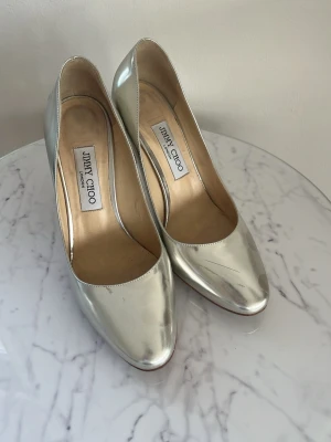 Jimmy Choo silver metallic pumps – storlek 39.5 + shoebox & dustbag - Säljer fina Jimmy Choo pumps i glansig silver metallic. Klassisk pointed toe med stilettklack. Bra skick på ovansidan, sulorna är använda men skorna är fortfarande jättefina! ✨ Allt ingår: original shoebox + dustbag. Made in Italy. Perfekta till fest och finare tillfällen. Nypris runt 5000+ kr. Frågor? Skriv gärna! Kan skickas snabbt 😊