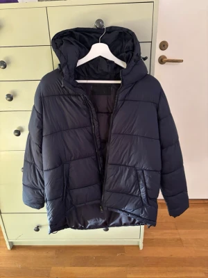 North Wood blå vinterjacka / täckjacka - Denna vinterjacka har jag använt någon enstaka gång i fjällen när jag åkt slalom, har två exemplar av denna jacka och säljer nu båda.   - Äldre säsongsmodell.  - Är asymmetriskt skuren, vilket innebär att den är något längre i modellen baktill. Storlek: M - Ordentlig fast huva, en rejäl innerficka, fickor på båda sidor med knappstängning - Justerbar dragsko nedtill i fållen för att kunna stänga ute vind - Material: Shell: 100% NYLON, padding: 100% POLYESTER, Lining: 100% POLYESTER