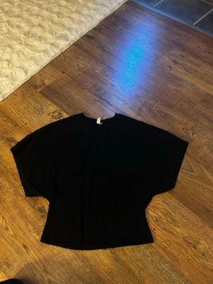 Svart topp från Nelly - Säljer en svart topp från Nelly med lös passform och breda ärmar. Perfekt till jeans eller kjol för en enkel men snygg look. Materialet känns mjukt och skönt mot huden.