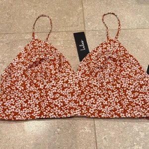 Röd blommig croptopp - Supersöt röd blommig croptopp från Lulus. Toppen har smockad rygg för extra komfort och bättre passform. Perfekt att styla till både jeans och kjol för en trendig look:) Aldrig använd, prislappen kvar. Säljs i befintligt skick. 