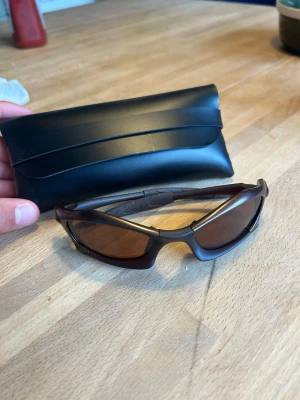 Oakley splice solglasögon  - Säljer ett par bruna oakley solglasögon med sportig, svepande form och smala skalmar. Glasen är mörka och bågarna har en snygg, aerodynamisk design. Perfekta för dig som vill ha en cool och funktionell look. Svart original fodral medföljer.
