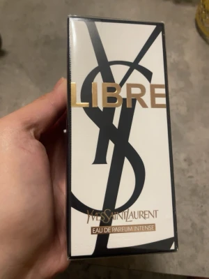 Yves Saint Laurent Libre Intense parfym - YSL Libre Eau de Parfum Intense är en lyxig parfym i en elegant, rektangulär glasflaska med guldiga detaljer och svart lock. Doften har en djup bärnstensfärg och flaskan pryds av den ikoniska YSL-loggan i metall. Perfekt för dig som gillar exklusiva dofter.