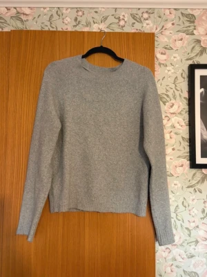 Ljusgrå stickad tröja - En stilren ljusgrå stickad tröja med rund halsringning och långa ärmar.