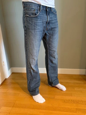 Levi’s 505 straight fit - Ett par blå jeans med rak passform och normal midja. Jeansen har fem fickor, dragkedjegylf och subtila slitningar för en avslappnad look. Tillverkade i denim med tydlig struktur och kontrastsömmar. Perfekta för en casual stil.