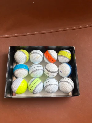 12 golfbollar från taylormade och srixon strips - Säljer ett dussin med 12 golfbollar i olika färger som vitt, gult, blått och orange. Några bollar har färgade band och synliga loggor, bland annat TaylorMade. Perfekt för dig som vill ha variation på golfbanan. 11 taylormade av tp5 och tour respons 1 srixon av z star⛳️👍
