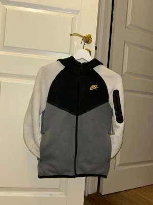 Nike hoodie i svart, grå och vit - Nike Tech Fleece hoodie med dragkedja, luva, många praktiska fickor och Nike logga i guld, storlek L                        (147-158)