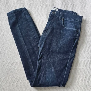Mörkblå jeans från Acne Studios W32L32 - Snygga mörkblå jeans från Acne Studios med klassisk femficksdesign och smal passform. Jeansen har en stilren look med diskreta slitningar och raka ben. Perfekta för dig som gillar minimalistisk och trendig stil.