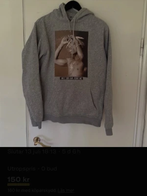 Grå hoodie med tryck och huva - Säljer en grå hoodie med stor huva och ett tryck på bröstet som föreställer en person med flera händer och texten 'Only God Can Judge Me'. Hoodien har ribbade muddar och magficka. Perfekt för dig som gillar streetwear och vill ha en chill look.
