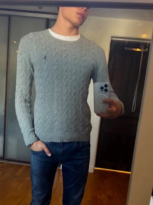Grå kabelstickad Ralph lauren sweater - Mycket fint skick – nästan som ny. Exklusiv kabelstickad Ralph Lauren-tröja i en mjuk och bekväm ull-/kashmirblandning. Nypris ca 3 100 kr. Han på bilden är 183 cm. Hör gärna av dig om du har några frågor! ⭐️