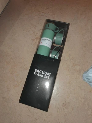 Grönt termosset med två muggar - Säljer ett vakuumflaskset med en grön termos på 500 ml och två matchande muggar. Termosen håller drycken varm eller kall i upp till 12 timmar. Allt kommer i en snygg presentförpackning. Perfekt för utflykter eller skolan. Helt nytt