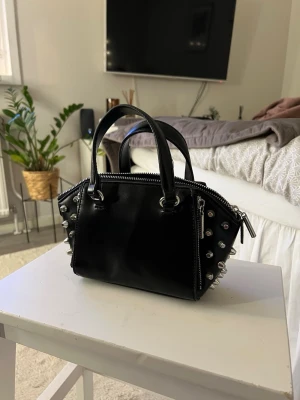 Svart handväska från Zara  - Snygg svart handväska med nitar från Zara. Väskan har inga defekter och är i mycket fint skick. Har endast använt några enstaka gånger. Tveka inte att höra av dig 💞
