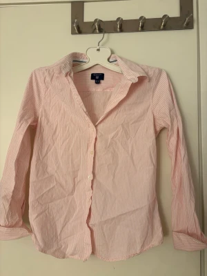 Rosa och vit randig skjorta från Gant - Klassisk skjorta från Gant i rosa och vitt randigt mönster. Perfekt till sommaren i en avslappnad outfit! Använd ett fåtal gånger!🩷🩷