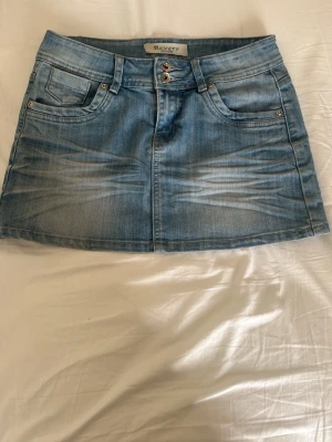 Blå jeanskjol från Revers - Snygg blå jeanskjol från Revers med klassisk femficksdesign, bälteshällor och dubbla knappar framtill. Kjolen har en kort passform. 💗💗