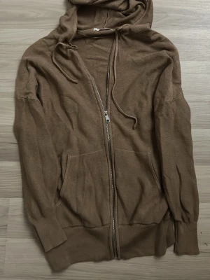 Beige hoodie med dragkedja från MNG - Snygg beige hoodie från MNG i storlek XS. Hoodien har dragkedja framtill, två fickor och justerbar huva med snören. Tillverkad i ett mjukt, stickat material som känns skönt mot huden. Perfekt för en avslappnad och chill stil.
