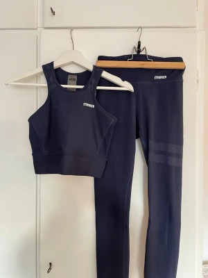 Mörkblått träningsset från Stronger - Snyggt mörkblått träningsset från Stronger med sport-topp och matchande tights. Setet har en stilren och snygg design, sitter väldigt fint på kroppen. Perfekt för gymmet eller löprundan.
