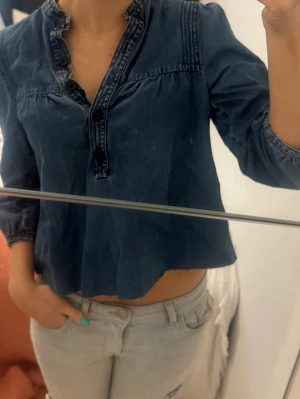 Mörkblå croppad blus - Säljer en mörkblå croppad blus med trekvartsärm och dekorativa sömmar.