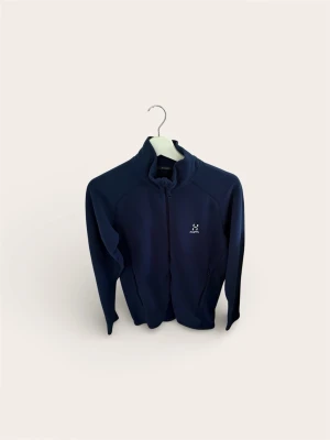 Haglöfs Fleece / Zip-tröja (Stl S) – Mörkblå - Säljer en klassisk och mångsidig fleecejacka/tröja från Haglöfs. Perfekt att ha som värmande mellanlager under skaljackan i skidbacken/skogen, eller bara som en skön vardagströja.  Modellen har hel dragkedja (full zip) och hög krage som skyddar mot vind. Mörkblå färg som funkar till allt.  Skick: Mycket fint skick! Inga hål, fläckar eller noppor. Dragkedjorna fungerar felfritt.  Storlek: Small (S). 