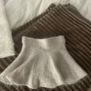 Beige fluffig kortkjol i mohair - Supersöt beige kortkjol med fluffig känsla och utsvängd form. Kjolen är stickad i mjuk mohair. Perfekt för dig som gillar en mysig och trendig stil. Ny utan prislapp!🤎