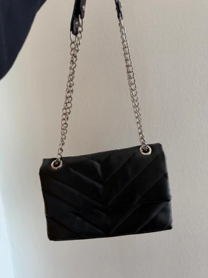 Svart axelväska med silver kedja - Svart axelremsväska med silver kedja.