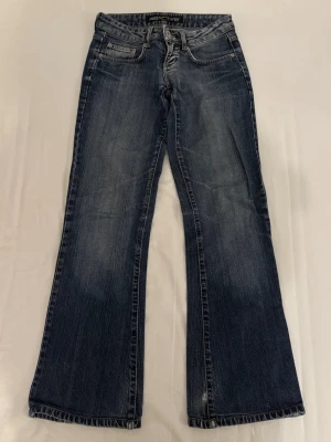 Mörkblå Reactive Jeans - Mörkblå utsvängda och lågmidjade jeans från Reactive med snygga dragkedjedetaljer på bakfickorna. Finns ett litet hål nertill på ena benet, annars i bra skick. Har själv aldrig använt dem då de är för små. MIDJEMÅTT: 34cm INNERBENSLÄNGD: 73cm