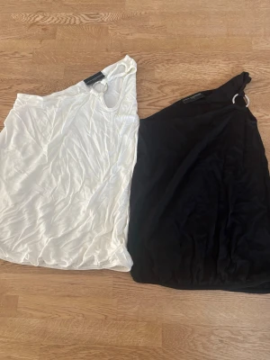 Två stycken Toppar - Två stycken toppar från Karin Andersson, aldrig använda💕den vita är storlek M och den svart S. Simpla en arms toppar med liten detalj. 40kr styck eller båda för 60kr💕