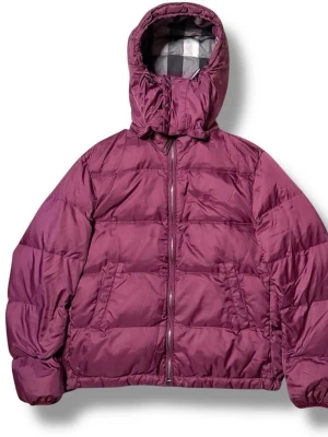 Vinröd pufferjacka från Burberry - Säljer en vinröd pufferjacka från Burberry med avtagbar huva och dragkedja framtill. Jackan har två snedställda fickor och klassiskt rutigt foder i huvan. Perfekt för kalla vinterdagar och riktigt snygg färg som sticker ut.