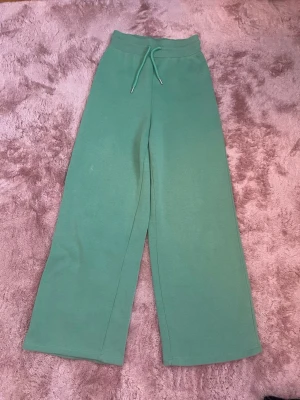 Gröna mjukisbyxor från NLY Trend - Snygga gröna mjukisbyxor från NLY Trend med bred resår i midjan och dragsko. Byxorna har raka, vida ben och är tillverkade i mjukt och skönt material som passar perfekt för en avslappnad stil, inte lika breda när man har på sig dem. Storlek XS passar även S, använd 1 gång