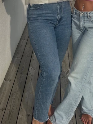 Blå raka jeans från Levis  - Säljer ett par klassiska blå jeans från Levis med rak passform och hög midja. Jeansen har råa, avklippta benslut. Perfekta för en avslappnad och trendig look. Storlek - W29 L31