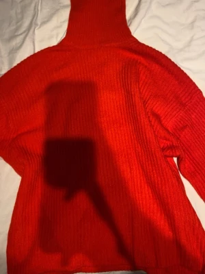 Röd polotröja i ribbstickat - Säljer en snygg röd ribbstickad polotröja med hög krage och lång ärm. Tröjan har en oversized passform och är gjord i mjukt material som känns skönt mot huden. Perfekt för dig som vill ha en färgklick i garderoben. Aldrig använd ❤️