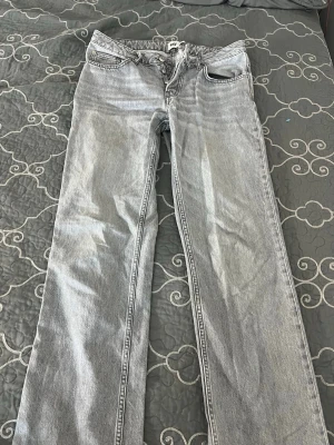 Ljusgrå raka jeans från lager 157  - Säljer ett par ljusgrå jeans från H&M med rak passform och klassisk femficksdesign. Jeansen har normal midja och är tillverkade i denim med en snygg tvättad look. Perfekta för en avslappnad och trendig stil.