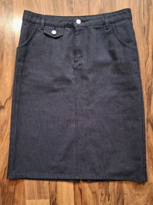 Filippa K Denim-Kjol i Medium – Klassisk minimalistisk Y2K - Made in italy - En Y2K Filippa K denim-kjol, producerad i Italien vilket knappt händer längre! Ett riktigt unikt och klassiskt fynd som är i toppskick! Denim-kjol med midjeknapp + dragkedja, treficks-modell. Storlek medium. Skick: Mycket fint använt skick – inga fläckar eller defekter.