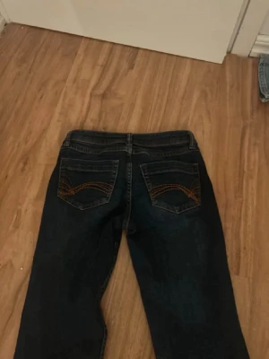 Mörkblå bootcut low waist jeans - Säljer ett par mörkblå bootcut jeans med snygga kontrastsömmar på bakfickorna. Jeansen lätt stretch. Perfekta för dig som gillar en avslappnad low waist jeans. Pris kan diskuteras 🫶