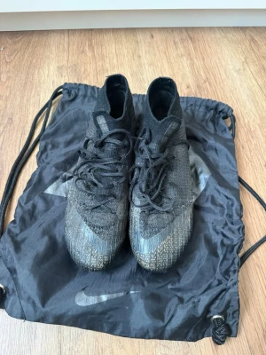 Nike Mercurial Superfly FG  - Fotbollsskor från Nike, Mercurial Superfly i svart färg. FG-dobbar för spel på naturgräs (gräsplan). 	•	Storlek: 40,5 	•	Underlag: FG (Firm Ground) 	•	Färg: svart 	•	Använda och har bl.a. slitage framme vid stortån.  	•	Dobbar i bra skick 	•	Original Nike-påse medföljer