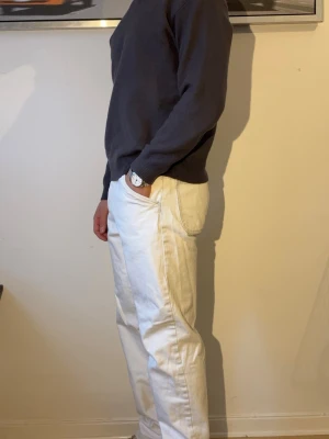 Straight leg vita jeans  - Säljer ett par vita jeans med rak passform och normal midja. Jeansen har fem fickor och tydliga sömmar längs benen. Materialet är kraftigt denim som ger en stilren look. Perfekta för dig som vill ha ett par ljusa jeans till din garderob.