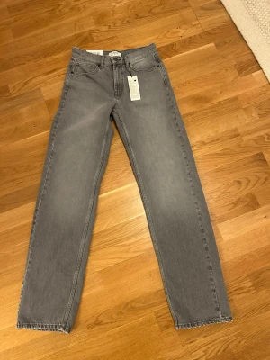  Ny Grå raka jeans från Lindex - Snygga grå jeans från Lindex med rak passform och klassisk femficksdesign. Jeansen har normal midja och är tillverkade i ett mjukt denimtyg. Perfekta för en avslappnad och trendig look.