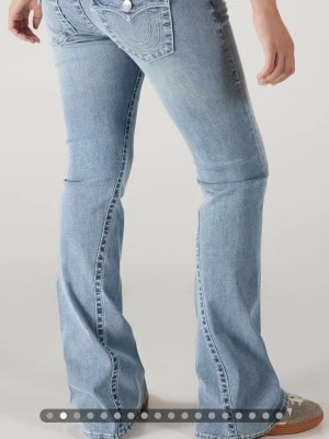 Bootcut jeans från True Religion - Snygga ljusblå bootcut jeans från True Religion med klassiska kontrastsömmar och ikoniska fickdetaljer bak. Jeansen har låg midja och är tillverkade i mjuk denim med lite stretch för extra komfort.