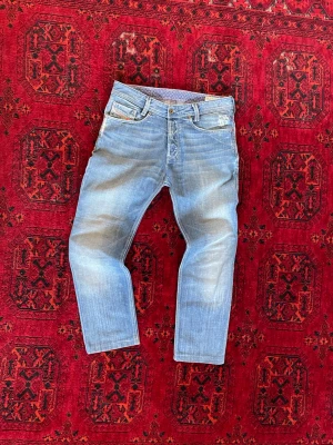 Diesel Jeans - Säljer ett par ljusblå jeans från Diesel med klassisk femficksmodell och snygga slitningar. Jeansen har raka ben och normal midja. Perfekta för dig som gillar en casual stil. Om du undrar något är det bara att skriva🙌