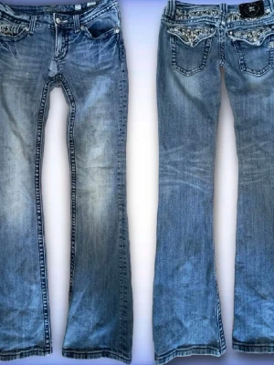 Blå bootcut jeans från Miss Me - Snygga blå bootcut jeans från Miss Me med slitningar och dekorativa detaljer på bakfickorna. Jeansen har låg midja, klassisk femficksmodell och silverfärgade knappar. Materialet är denim utan stretch. Köpta på plick, små defekter som har syts igen, se bild 4 & 5💕innerbenslängd: 84cm midjemått: 38cm rakt över