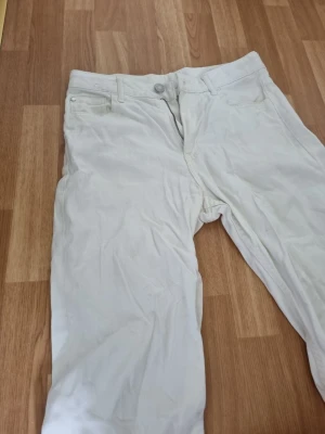 Vita raka jeans - Snygga vita jeans med rak passform och klassisk femficksdesign. Jeansen har bälteshällor och stängs med knapp och dragkedja. Perfekta för en fräsch och stilren look.