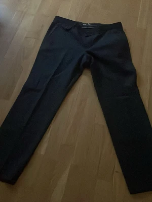 Mörkblå kostymbyxor från BOSS - Snygga mörkblå kostymbyxor från BOSS med klassisk rak passform och diskreta fickor. Perfekta för en stilren look och passar till skjorta eller kavaj. Materialet känns mjukt och exklusivt, vilket ger en lyxig känsla.