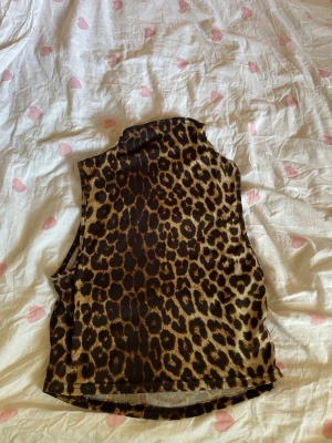 Leopardmönstrad ärmlös polotopp - Säljer en leopardmönstrad ärmlös polotopp i stretchigt material. Toppen har hög krage och är perfekt för dig som vill sticka ut med ett djurmönster. Passar snyggt till både jeans och kjol.
