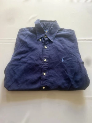 Ralph lauren skjorta - Ralph Lauren skjorta, marinblå, storlek S. Ikonisk modell med broderad logga och klassisk buttondown krage. Mjuk och bekväm bomull som passar lika bra till vardags som till lite finare tillfällen. Mycket fint skick!