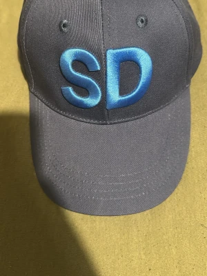 SD-keps - Säljer ett autentiskt SD keps,har bevis att den är direkt från just SD själv.kepsen kommer även med ett armband