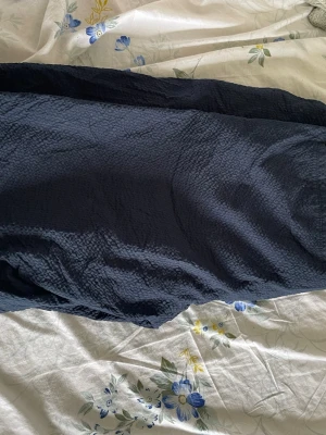 Mörkblå loose shorts i bomull - Säljer ett par mörkblå shorts med loose passform. De är tillverkade i ett strukturerat bomullstyg som ger en avslappnad känsla. Perfekta för varma dagar och har en enkel, stilren look utan synliga detaljer.