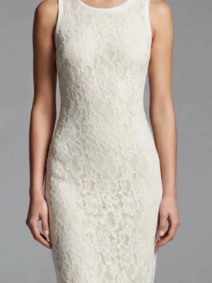 Vit spetsklänning med blommönster - Elegant vit klänning i figurnära modell med vackert blommigt spetsmönster. Ärmlös design och rund halsringning, perfekt för sommarens alla tillfällen. Klänningen har en liten öppning i ryggen för extra detalj.